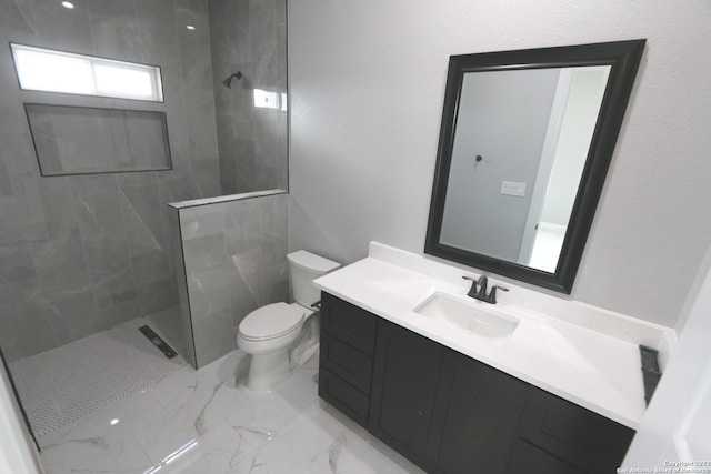 bathroom featuring vanity, toilet, and a tile shower