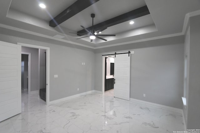 unfurnished bedroom with ornamental molding, ceiling fan, a tray ceiling, a barn door, and ensuite bath