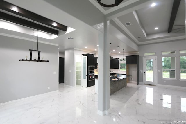 kitchen featuring crown molding, pendant lighting, stainless steel microwave, and a tray ceiling