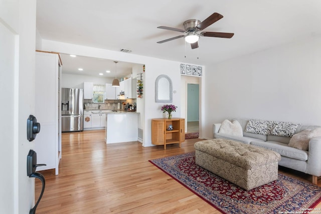 living room with light hardwood / wood-style flooring and ceiling fan