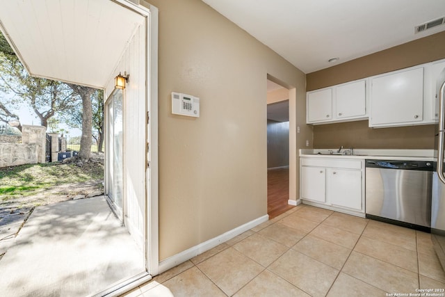 kitchen featuring white cabinets, light tile patterned floors, stainless steel dishwasher, and sink