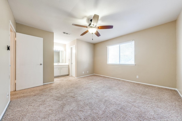 unfurnished bedroom featuring connected bathroom, ceiling fan, and light colored carpet