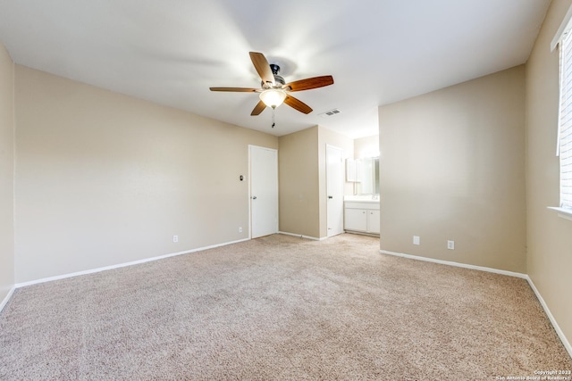 unfurnished bedroom with light carpet, multiple windows, ensuite bath, and ceiling fan