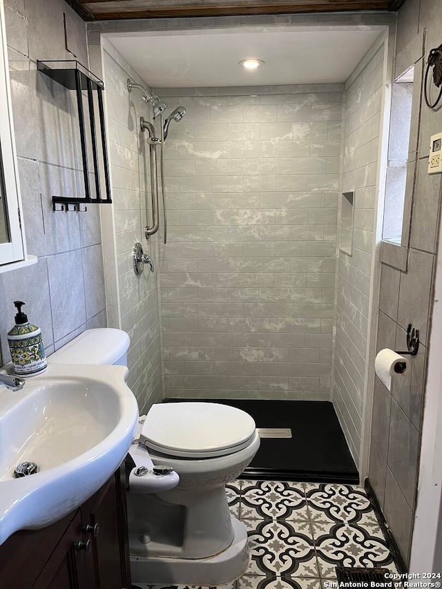 bathroom featuring tile walls, toilet, a tile shower, and vanity