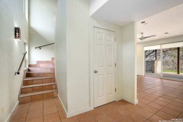 stairs with ceiling fan and tile patterned floors