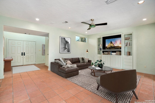 living room featuring light tile patterned flooring, ceiling fan, a textured ceiling, and built in shelves