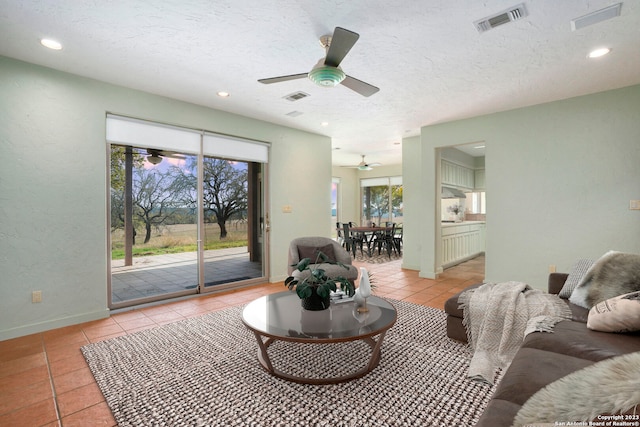 living room featuring light tile patterned flooring, ceiling fan, and a textured ceiling