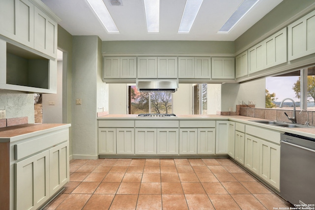 kitchen with stainless steel appliances, kitchen peninsula, sink, light tile patterned floors, and exhaust hood