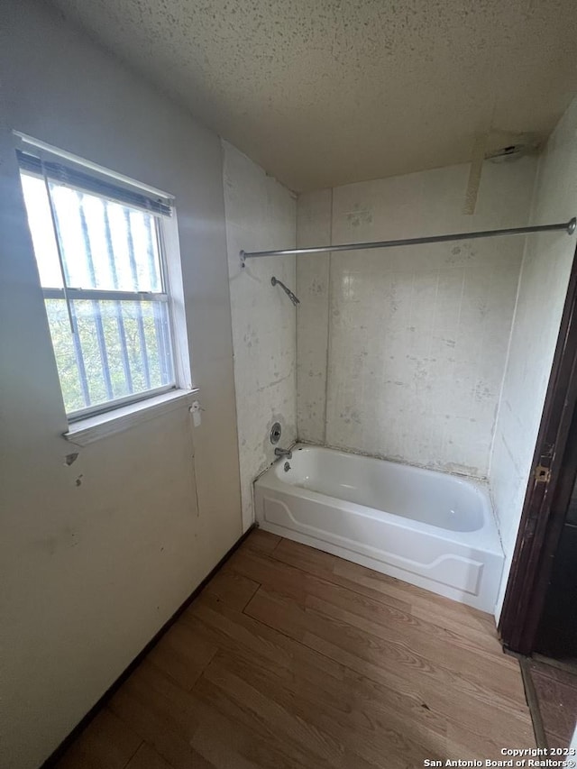 bathroom featuring tiled shower / bath combo, a textured ceiling, and hardwood / wood-style flooring