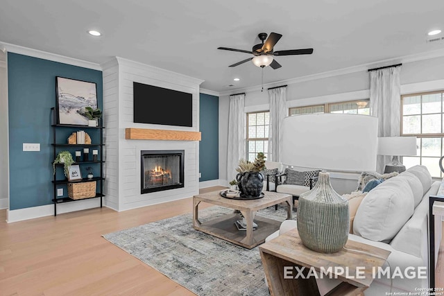 living room with a wealth of natural light, a fireplace, light wood-type flooring, and crown molding