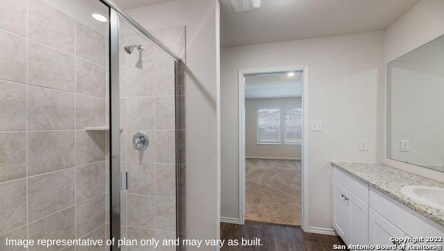 bathroom with hardwood / wood-style floors, vanity, and a shower with shower door