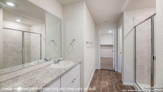 bathroom featuring hardwood / wood-style flooring, vanity, and walk in shower