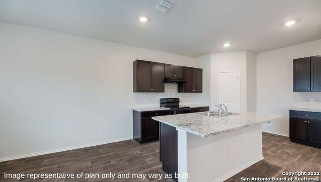 kitchen featuring electric range, sink, dark hardwood / wood-style flooring, a kitchen island with sink, and dark brown cabinets