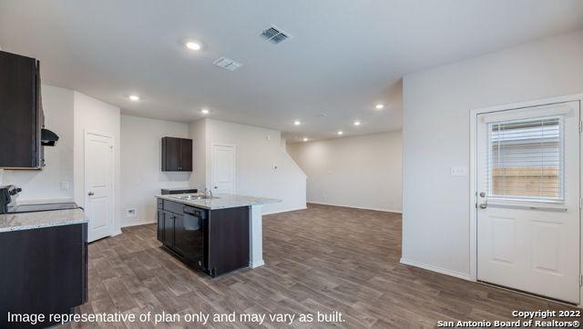 kitchen featuring dishwasher, stove, a kitchen island with sink, and dark wood-type flooring