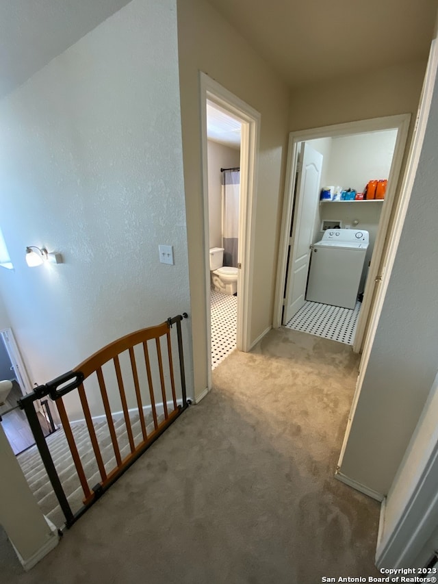 hall with washer / dryer and light carpet