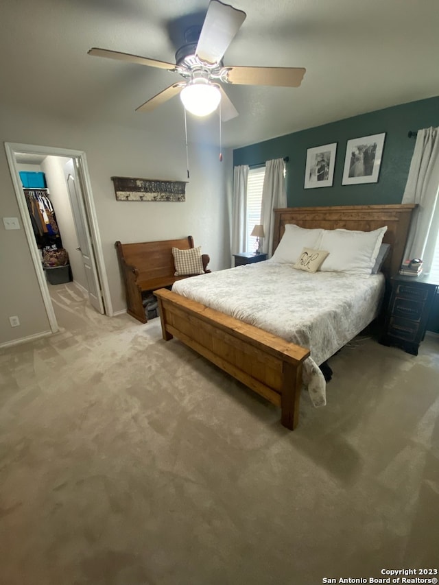 bedroom featuring ceiling fan, a walk in closet, light carpet, and a closet