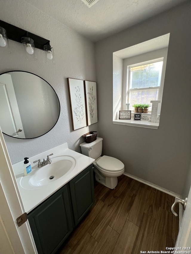 bathroom with hardwood / wood-style floors, vanity, a textured ceiling, and toilet