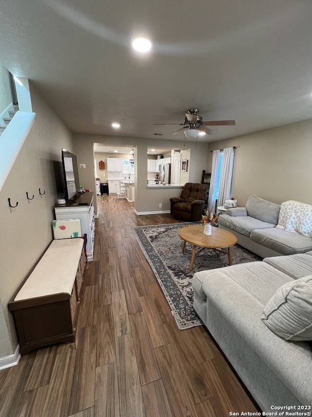 living room featuring ceiling fan and dark hardwood / wood-style flooring