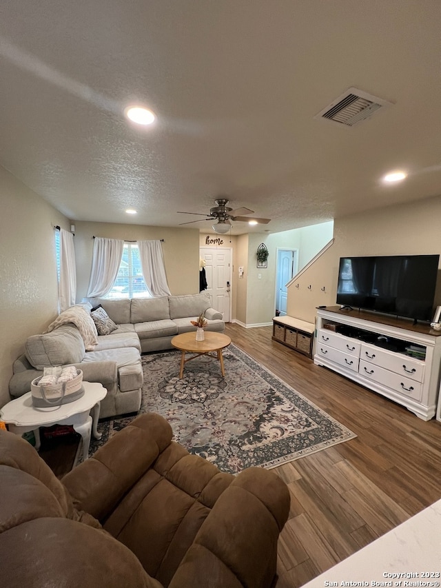 living room with ceiling fan, dark hardwood / wood-style flooring, and a textured ceiling