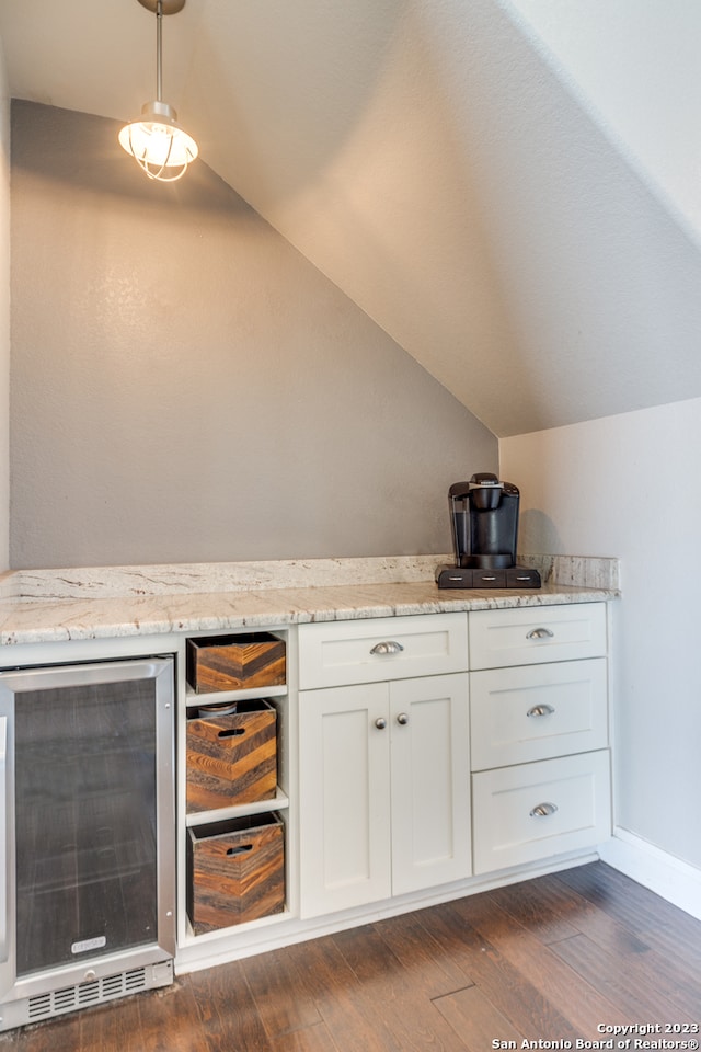 interior space with white cabinets, dark hardwood / wood-style floors, light stone countertops, lofted ceiling, and beverage cooler