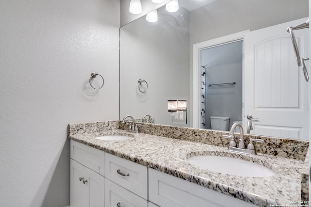 bathroom featuring toilet and double sink vanity