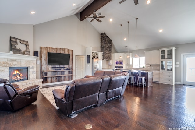 living room with a fireplace, ceiling fan, wood-type flooring, and beam ceiling