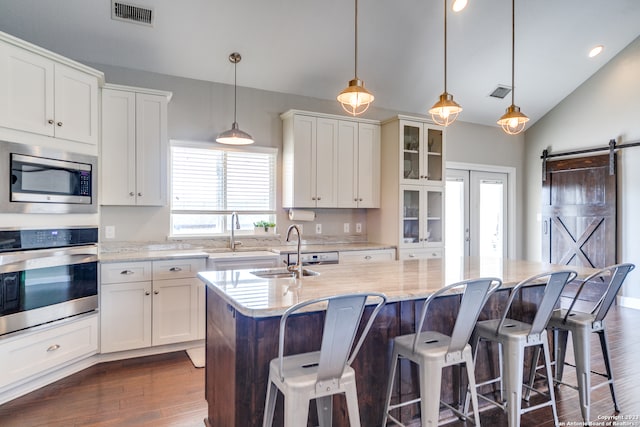 kitchen featuring hanging light fixtures, dark hardwood / wood-style floors, an island with sink, and stainless steel appliances