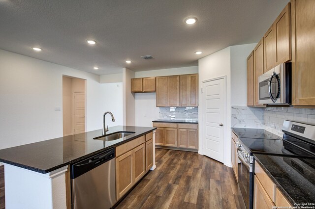 kitchen with sink, dark wood-type flooring, stainless steel appliances, decorative backsplash, and a kitchen island with sink