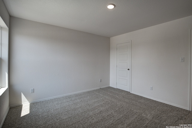 spare room with dark colored carpet