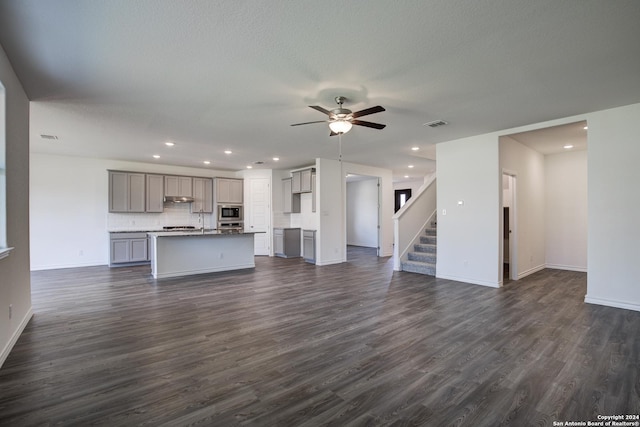 unfurnished living room with ceiling fan and dark wood-type flooring