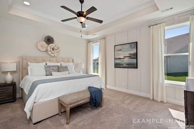 carpeted bedroom featuring a tray ceiling and ceiling fan