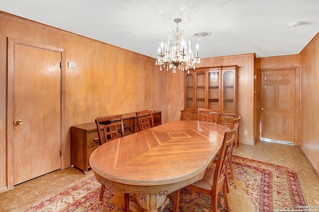 dining space featuring a chandelier and wood walls