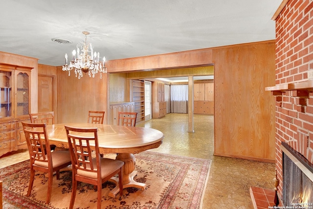 dining room with wood walls, a chandelier, a brick fireplace, ornamental molding, and built in features