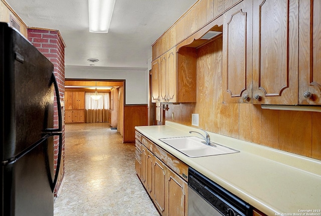 kitchen featuring dishwasher, black fridge, sink, and wooden walls