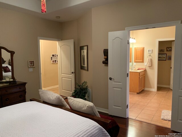 bedroom with connected bathroom and light wood-type flooring