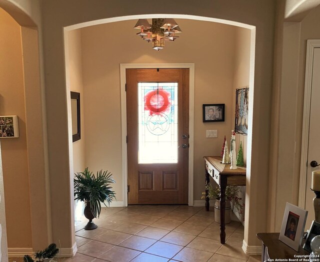 tiled entrance foyer with a chandelier