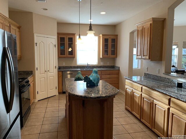 kitchen with dishwasher, light tile patterned floors, dark stone counters, and sink