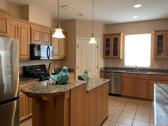 kitchen featuring a center island, dark stone counters, ceiling fan, decorative light fixtures, and light tile patterned flooring