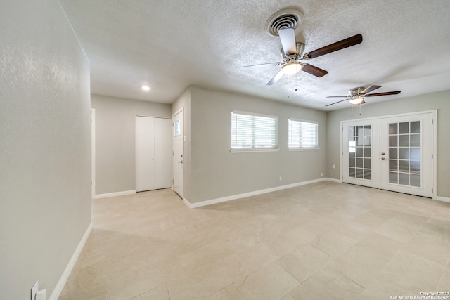 tiled spare room featuring a textured ceiling, ceiling fan, and french doors