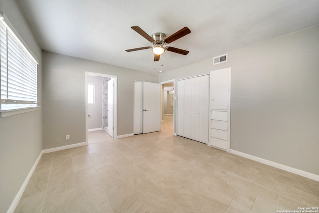 unfurnished bedroom featuring light tile patterned flooring, a closet, ensuite bath, and ceiling fan