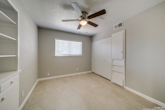 unfurnished bedroom featuring a closet, light tile patterned floors, a textured ceiling, and ceiling fan