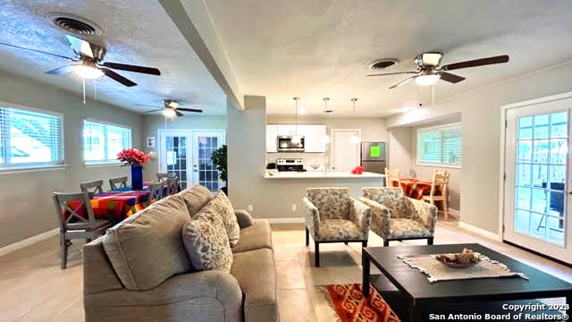 living room with french doors, ceiling fan, and a healthy amount of sunlight