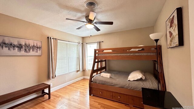 bedroom featuring a textured ceiling, light wood-type flooring, and ceiling fan