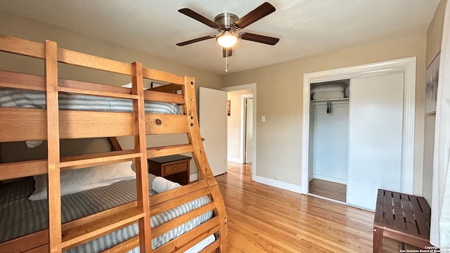 bedroom with light hardwood / wood-style floors, ceiling fan, and a closet