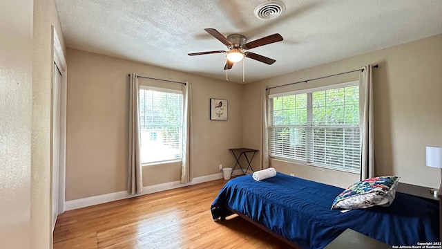 bedroom with ceiling fan, a textured ceiling, and light wood-type flooring