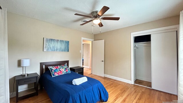 bedroom featuring a textured ceiling, a closet, wood-type flooring, and ceiling fan