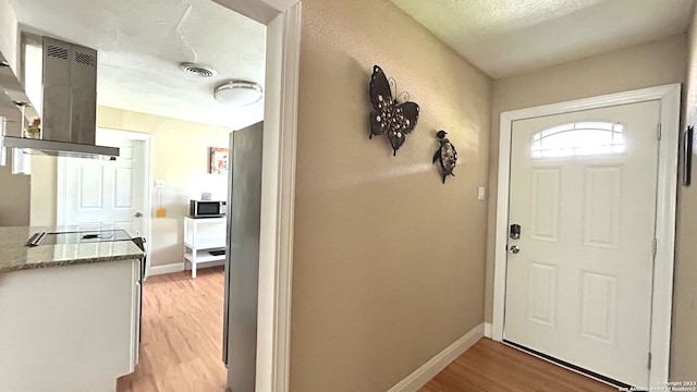 entrance foyer featuring a textured ceiling and light wood-type flooring