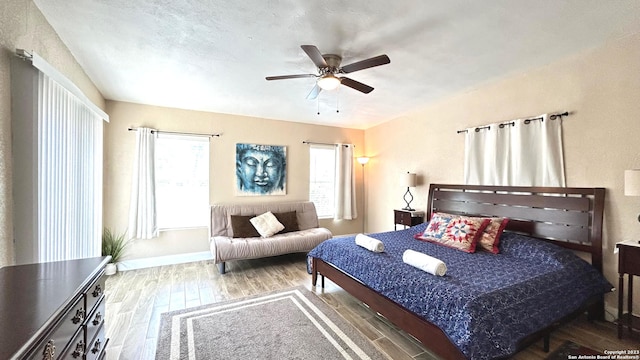 bedroom featuring multiple windows, wood-type flooring, and ceiling fan