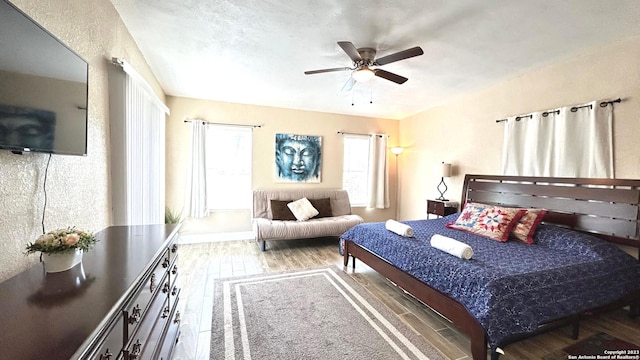 bedroom featuring multiple windows, hardwood / wood-style floors, and ceiling fan