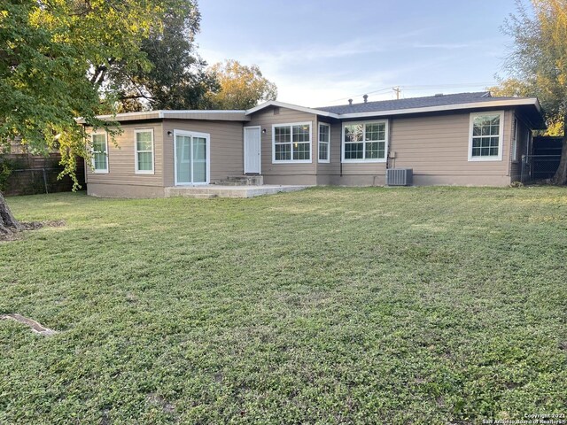 rear view of house with a lawn and cooling unit